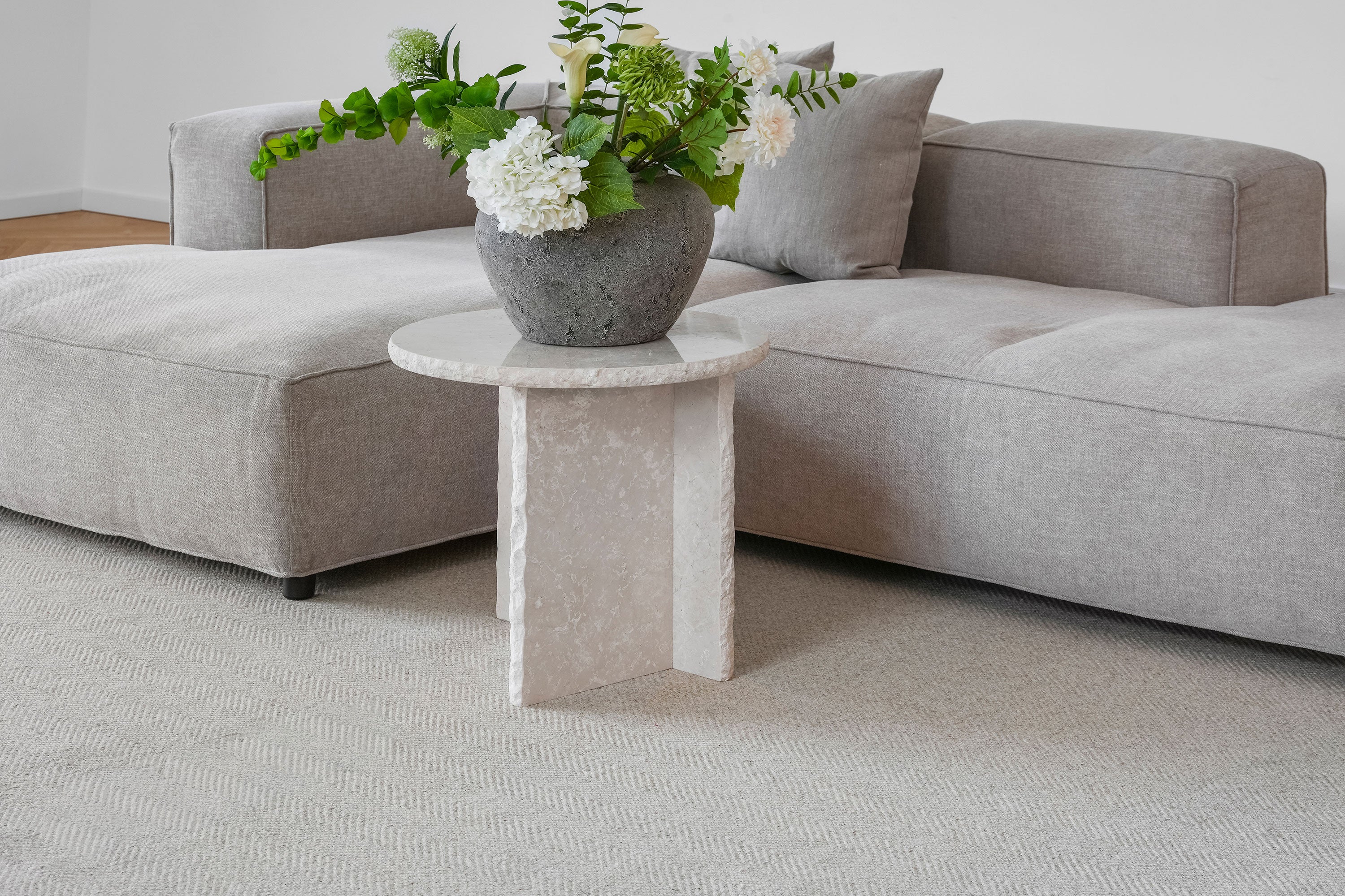 Fladvævet uldtæppe i lys beige under sofa og sidebord – Vosper jacquard tæppe med roligt udtryk