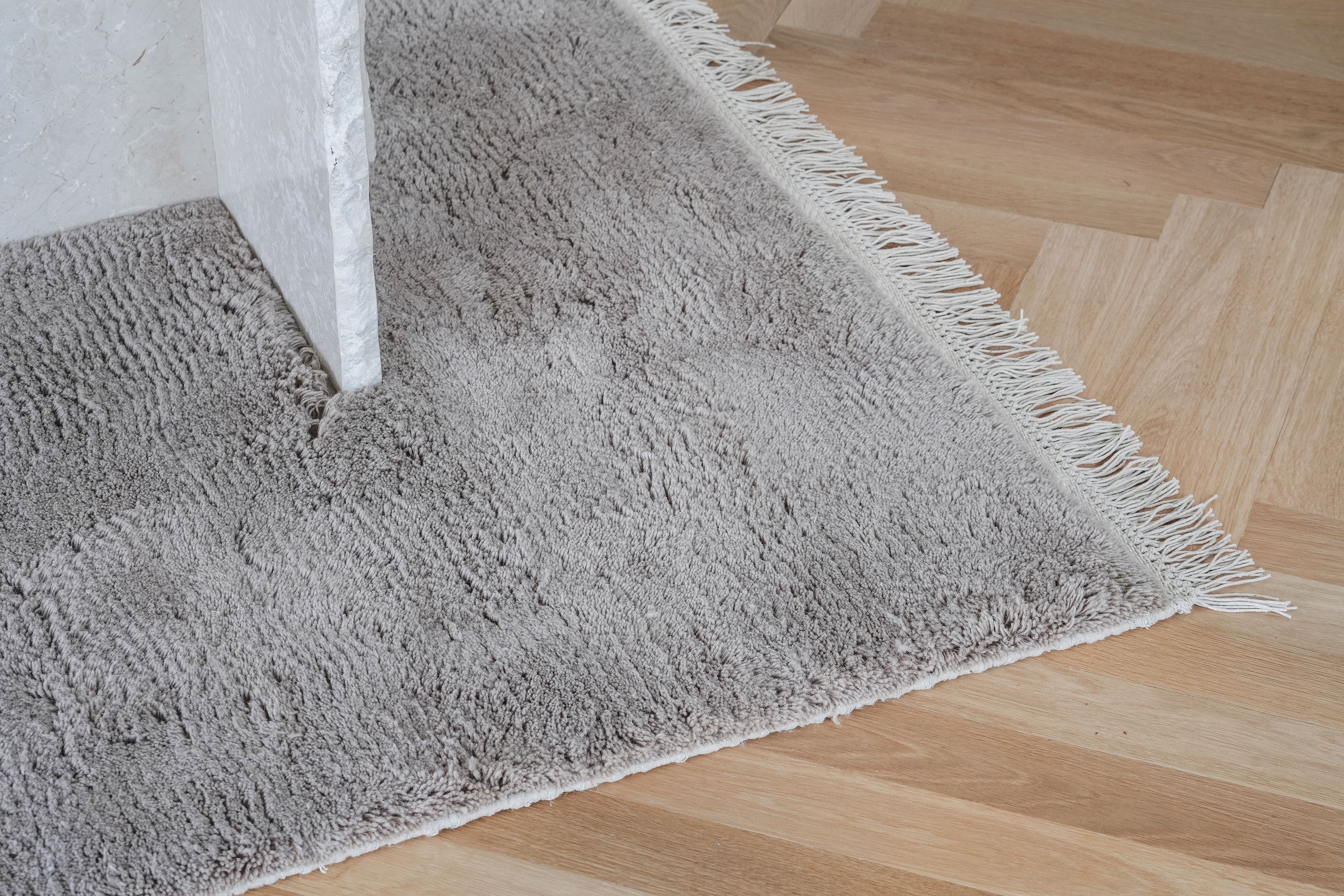 Detalje af uldtæppe i taupe med struktur og kant – Vosper UniShag Wool